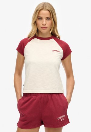 Rood en crèmekleurig, T-shirt met korte mouwen en raglanstijl met "Superdry" logo en bijpassende rode shorts met geborduurde tekst "Superdry NYC". Zachte, casual stof.