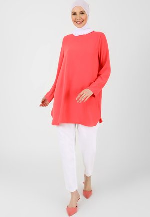 Coral tunic top with long sleeves, rounded hem; paired with white slim-fit pants and pink pointed flats. White headscarf completes the look.