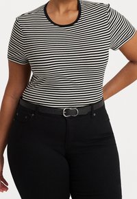 Black and white striped short-sleeve t-shirt with a round neckline, paired with high-waisted black jeans and a black belt featuring a silver buckle.