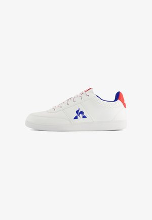 White leather sneaker with blue and red accents, perforated details, textured sole, and patterned laces featuring a logo on the side.