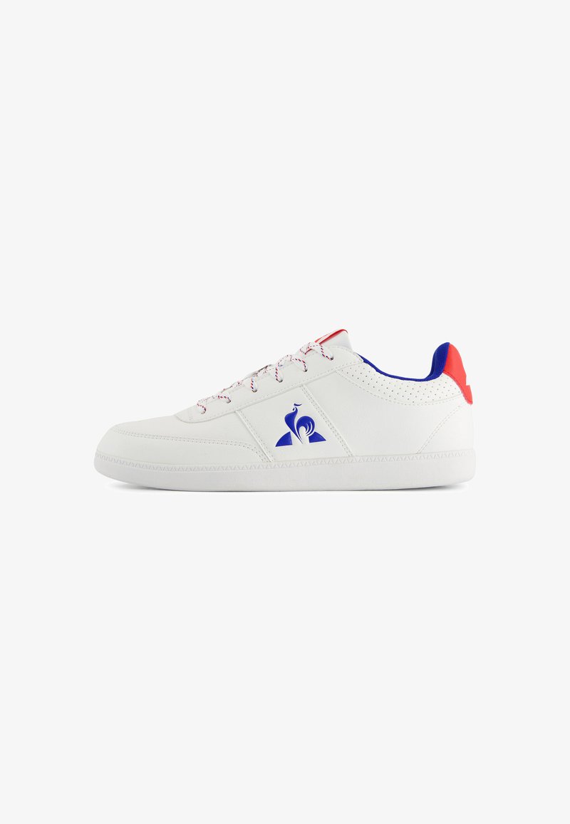 Baskets en cuir blanc avec des accents bleus et rouges, détails perforés, semelle texturée et lacets à motifs avec un logo sur le côté.