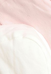 Due abiti in tessuti di un rosa chiaro e bianco, caratterizzati da un delicato motivo testurizzato con piccoli punti in rilievo e bordi lisci e arrotondati.