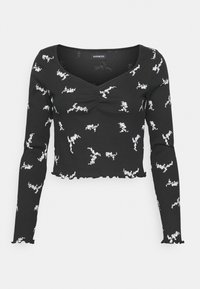 Černý dlouhý rukáv cropped top s nařaseným předním dílem a bílými abstraktními vzory. Obsahuje volánkový lem a měkkou, texturovanou tkaninu.