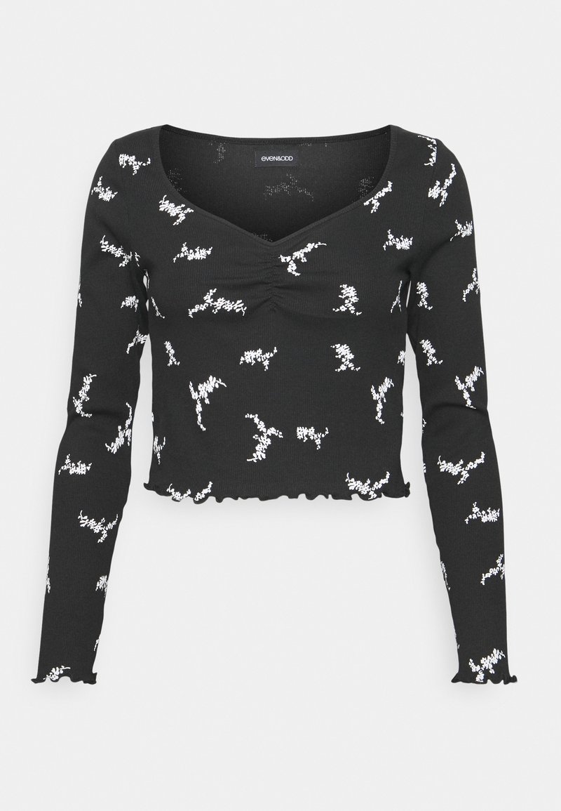 Černý dlouhý rukáv cropped top s nařaseným předním dílem a bílými abstraktními vzory. Obsahuje volánkový lem a měkkou, texturovanou tkaninu.