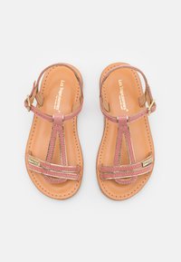 Sandales en cuir marron avec une sangle tressée rose, design en T, et une boucle dorée. Texture lisse avec une bordure cousue.