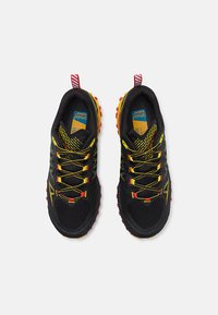 Črne športne čevlje z rumenimi detajli, mrežastim zgornjim delom in strukturiranimi rdečimi podplati. Imajo vezalke, odsevne podrobnosti in zanko na peti.