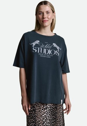 Dunkelgraues, übergroßes T-Shirt mit gerippter Textur und weißem Grafikdruck. Kombiniert mit einem Rock im Leopardenmuster, der einen geraden Schnitt hat.