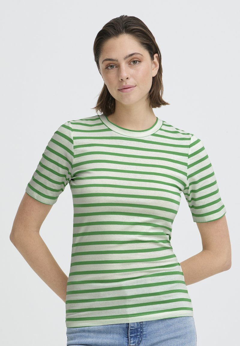 T-shirt à rayures vertes et blanches en coton doux, avec un col rond et des manches courtes. Coupe ajustée avec une texture lisse.