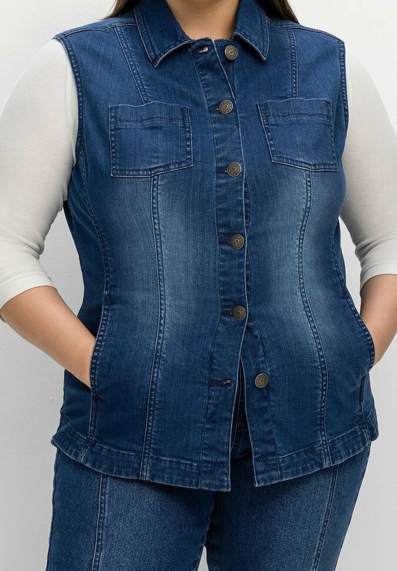 Denimväst i mörkblått med krage, knappstängning, två bröstfickor och en figursydd design. Har en lätt vadderad struktur.