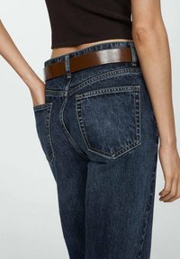 Jeans de mezclilla azul oscuro de cintura alta, con un cinturón marrón brillante y dos bolsillos traseros, que muestran un acabado texturizado.