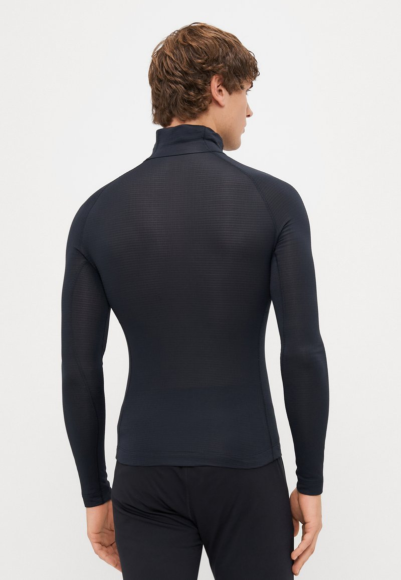 Langemouw top in donker marineblauw, gemaakt van een gestructureerd, aansluitend materiaal met een schijnhalssluiting. Heeft een naadloze constructie en een zachte afwerking.