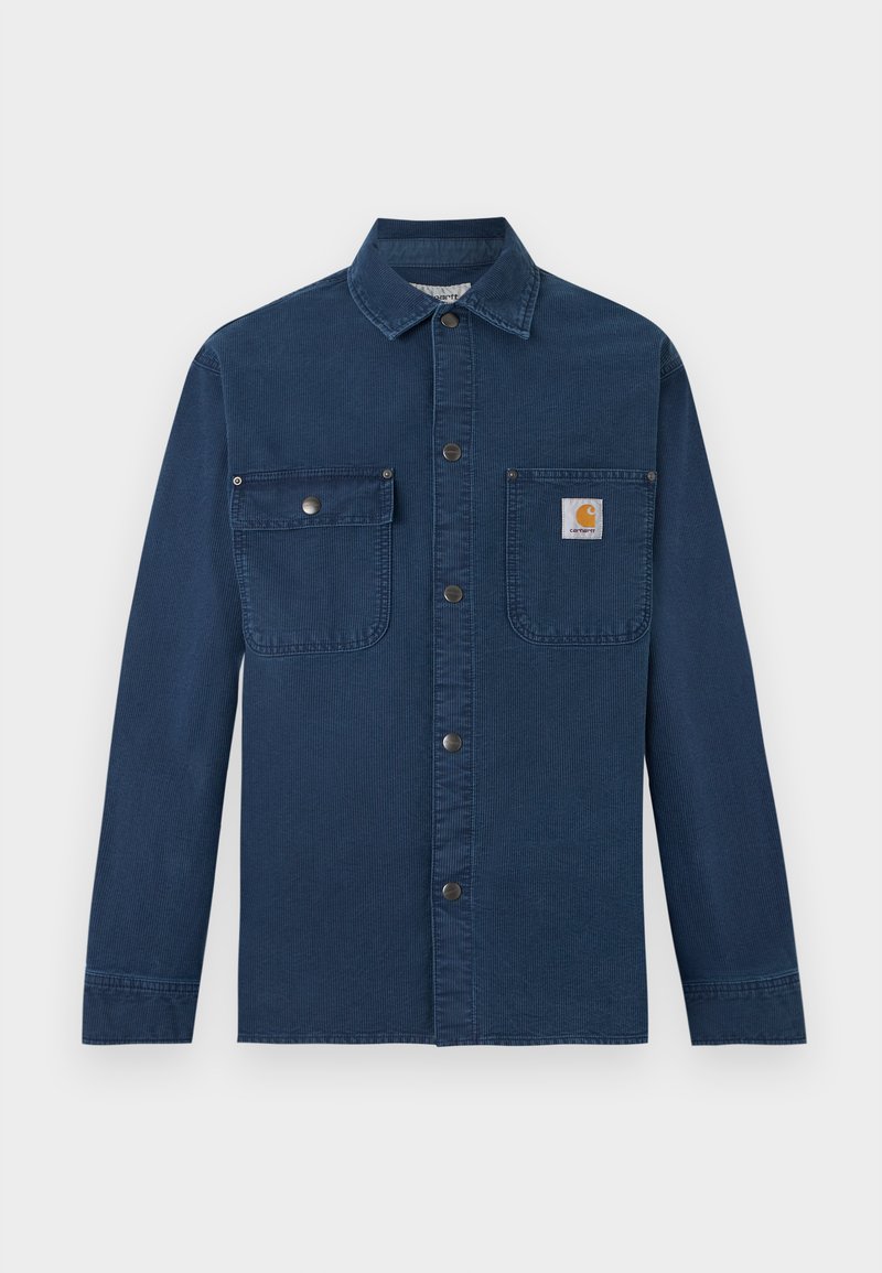 Marineblaues Cord-Arbeitshemd mit langen Ärmeln, Druckknopfverschluss vorne, zwei Brusttaschen und kleinem Carhartt-Logo auf der rechten Tasche.