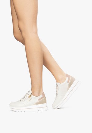 Baskets beiges avec accents en daim et cuir, œillets métalliques, col rembourré et semelle en caoutchouc texturée. Design à bout arrondi.