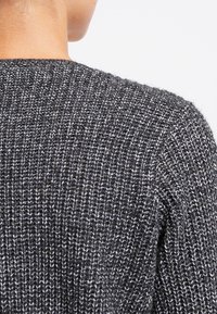 Textured black and gray knitted sweater with a ribbed design, showcasing a blend of fibers. The back features a round neckline and subtle detailing.