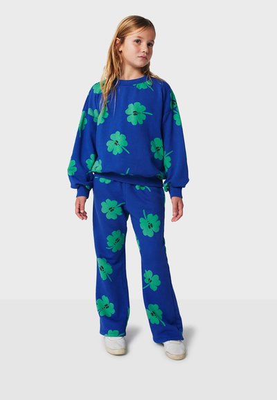 Ensemble de sweat-shirt et pantalon bleu avec de grands motifs de fleurs vertes. Le tissu semble doux avec une coupe décontractée et des poignets élastiques.
