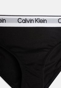 Čierne bavlnené trenýrky s bielym elastickým pásom, na ktorom je v čiernej farbe vytlačené "Calvin Klein". Hladká textúra a klasický dizajn.