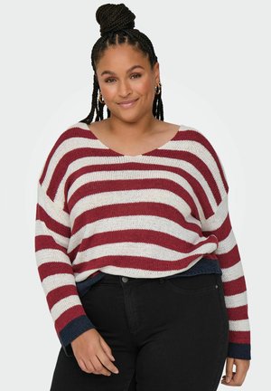 Striped sweater in red and cream, lightweight knit fabric, wide neckline, loose fit, with dark blue cuffs and hem. Paired with black jeans.