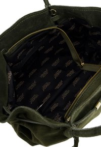 Kabelka z olivově zelené semiše se zipovým uzávěrem, uvnitř černá podšívka s logovanými vzory a vnitřní kapsa pro organizaci.