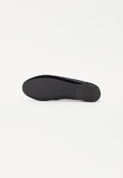 Black flat shoe with a textured, woven upper and a smooth rubber sole. Features a low profile and minimalistic design. Size 37 marked.