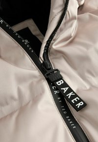 Giacca a vento in satin rosa chiaro con cerniera nera. Presenta un'etichetta con il marchio lungo la cerniera con testo bianco su una fascia a contrasto.