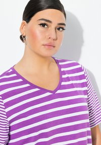 Camiseta de cuello en V de rayas moradas y blancas con mangas cortas, hecha de tela suave, con un ajuste relajado y una textura sutil.