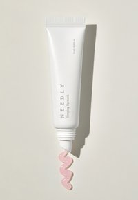 Tubo bianco con tappo rigato, etichettato "NEEDLY Sleeping Lip Mask." Un prodotto rosa chiaro e ondulato viene spremuto dalla punta. Design semplice.