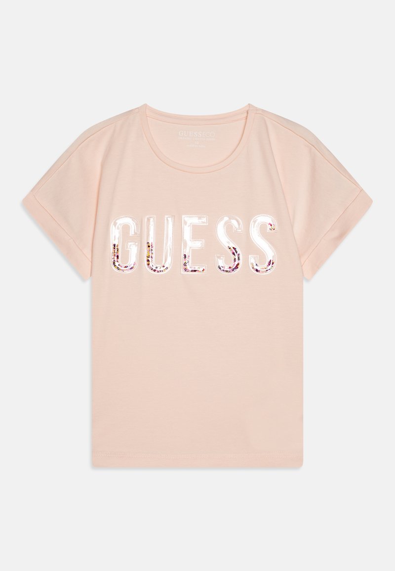 Gaiši rozā kokvilnas T-krekls ar īsām piedurknēm, rotāts ar sekvīnu greznotu "GUESS" logo uzdruku drosmīgā fontā. Apaļš kakla izgriezums, brīva piegriezuma stils.