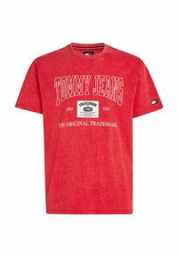 Camiseta de algodón roja con el logo "TOMMY JEANS", texto de 1985 y un gráfico rectangular. Mangas cortas y cuello redondo. Textura suave.