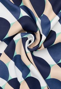 Gemusterter Stoff mit geometrischen Formen in Marineblau, Creme und Minzgrün, der eine glatte Textur hat und sanft gefaltet ist, um das Design zu zeigen.