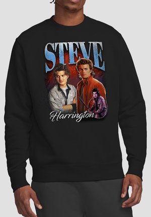 Schwarzer Pullover mit drei Porträts eines Mannes, darüber in großen blauen Buchstaben "STEVE" und darunter in weißer Schrift "Harrington".