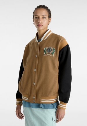 Veste varsity marron et noire avec des poignets et un col rayés, arborant un patch logo sur la poitrine, fabriquée en tissu doux et texturé.