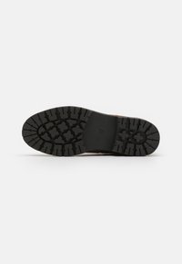 Black rubber outsole with deep tread pattern, featuring raised stars and a textured surface for traction. Smooth edge with "57" stamped.