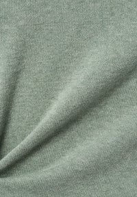Lichtgroene gebreide stof met een gladde textuur, voorzien van een subtiel patroon. Het materiaal lijkt zacht en licht elastisch.