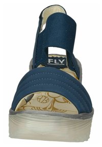 Sandalia textil azul con una correa acolchada para el tobillo, parte superior a rayas y una suela de goma texturizada. Presenta un interior con diseño.