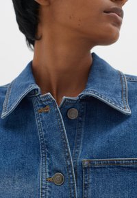 Modra jeans jakna z opozorjeno ovratnikom, srebrnimi gumbi na klik, vidnim šivanjem in detajlom prsne žepne. Mehak material z nenamenskim dizajnom.