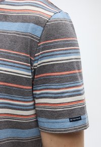 Πουκάμισο με κοντά μανίκια από γκρι βαμβάκι με οριζόντιες ρίγες σε μπλε, κόκκινο και λευκό. Διαθέτει λογότυπο στο τελείωμα και απαλή υφή.