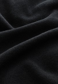 Črno tkanje z vidnim reliefnim vzorcem, ki prikazuje mehak, mat videz in gladko padajoč material.