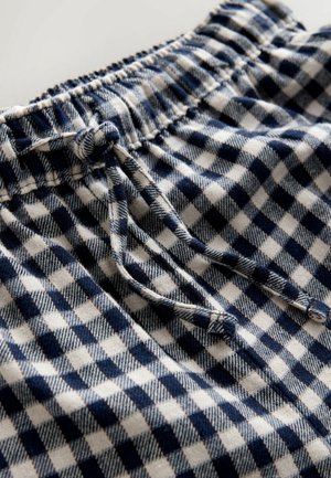 Puuvillashortsit, joissa on sinivalkoinen ruutukuosi. Elastinen vyötärö ja nauha säädettävää istuvuutta varten. Teksturoitu kangas.