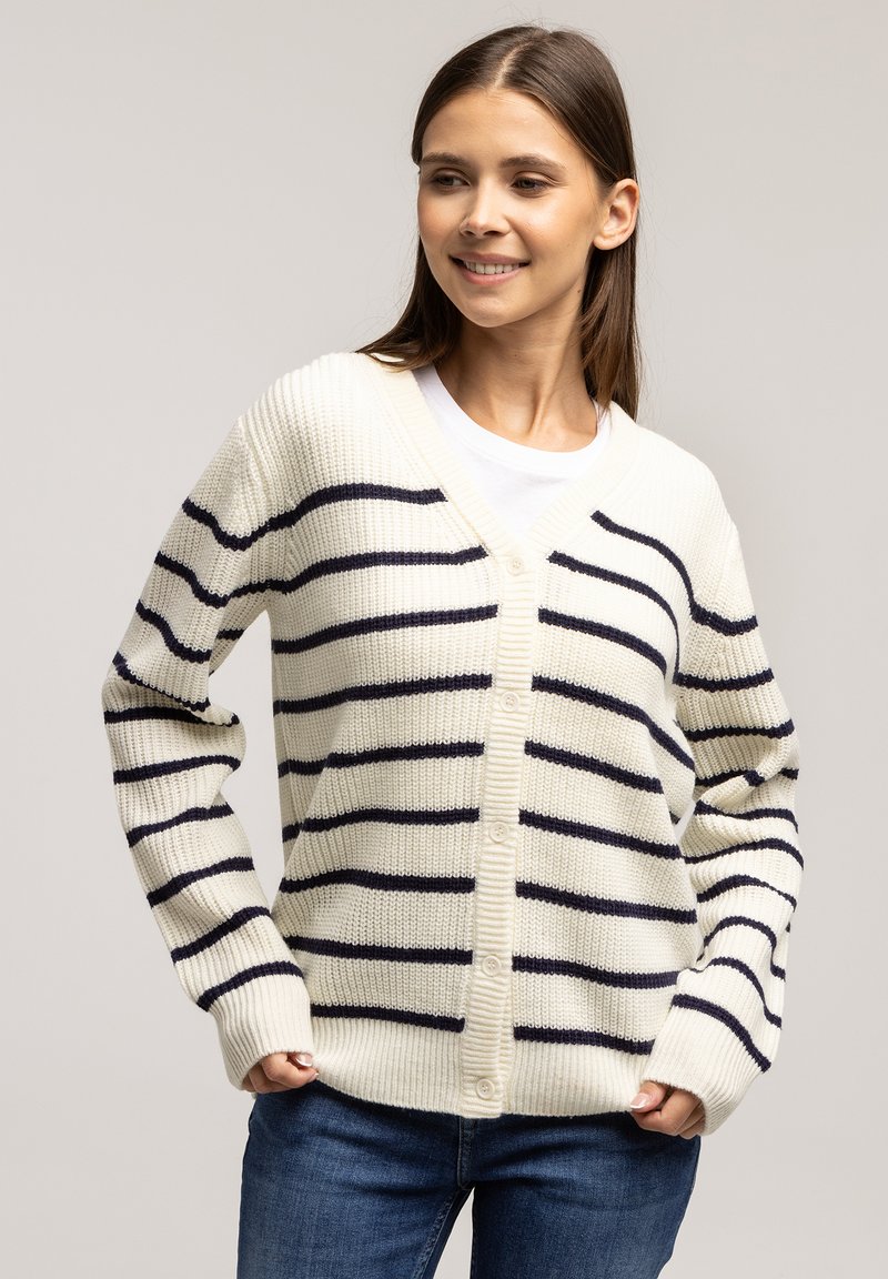 Kremowy kardigan w granatowe paski, z dekoltem w serek, zapinany na guziki i ściągaczami przy mankietach. Dzianinowa tekstura i luźny krój.