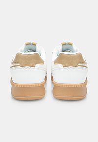 White and tan sneakers with a smooth leather upper, textured beige rubber soles, and a padded collar. Back features two light-colored stripes.