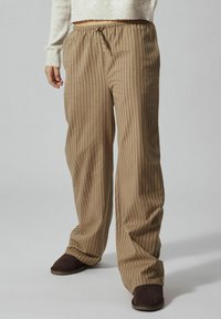 Pantalons à rayures beiges avec une coupe décontractée, taille élastique et cordon de serrage. Tissu texturé avec des rayures verticales pour un détail supplémentaire.