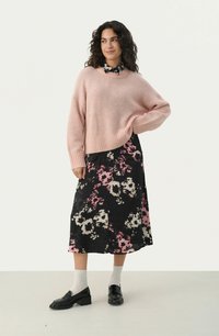 Pulover tricotat roz pal cu tiv elastic, purtat peste o fustă maxi florală neagră cu flori roz și albe, asortat cu mocasini negri.