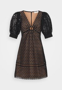 Robe noire en crochet avec un col en V, des manches bouffantes, un détail circulaire à la taille et une superposition de motif transparent. Fermeture éclair au dos.