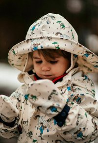 Wasserabweisender, cremiger Regenmantel mit Illustrationen von Tieren und Kindern. Enthält einen passenden breitkrempigen Hut und Handschuhe mit einer strukturierten Oberfläche.