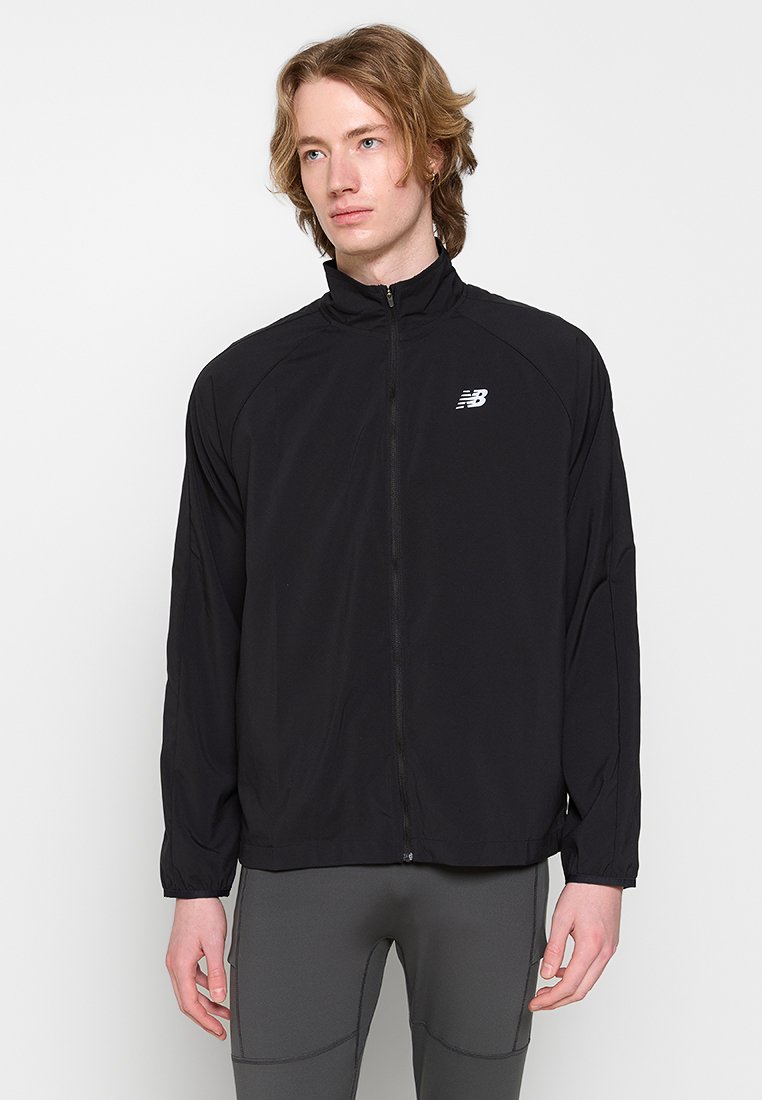 Zwarte sportjack met een hoge kraag, volledige ritssluiting aan de voorkant en het New Balance-logo op de linkerkant van de borst. Glad textuur en lichtgewicht ontwerp.