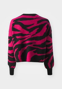 Rosa och svart oversized tröja med ett djärvt zebramönster, rund halsringning och ribbade ärmslut. Stickad textur med en avslappnad passform.