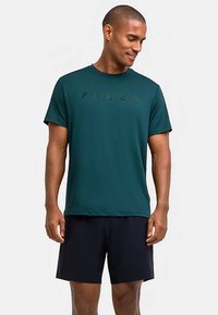 Donkerblauwgroen sportshirt met korte mouwen en een ronde hals, met het woord "FALKE" in zwarte letters op de borst.