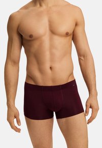 Burgundské boxerky vyrobené z měkké, pružné látky s přiléhavým střihem a kontrastním prošitím, s přední kapsou.