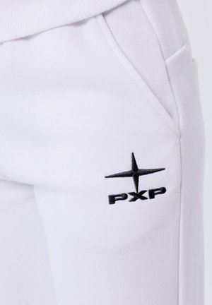 Pantalones de chándal blancos con bolsillos laterales que presentan un logo bordado en negro 'PXP' y un diseño de estrella en el muslo superior. Textura de tela suave.