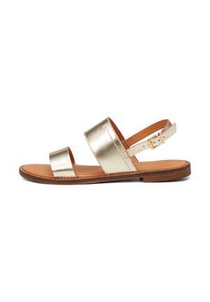 Metallische gouden platte sandalen hebben twee brede banden, een verstelbare enkelband met een gesp en een bruine leren voetbed. Laag profiel zool.